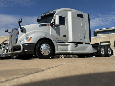Kenworth T680 conventional sleeper tractor in silver, side view showing cab with sleeper, front bumper and chrome wheels.