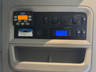 Kenworth T680 dash showing control panel with circular climate knobs, digital display, and various switches in a sleeper tractor cab.