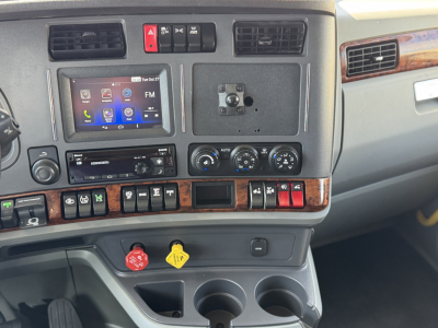 Kenworth T680 dash panel with touchscreen display and control switches in a truck cab.