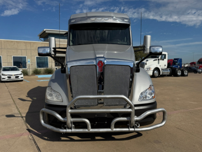 Kenworth T680 front view showing large grille, bumper guard, and dual chrome exhaust stacks. Visible text includes no legible labels on the bumper; general truck silhouette.