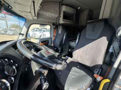Kenworth T680 truck interior showing steering wheel, dashboard, and driver seat with sleeper cab area in view.