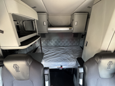 Kenworth T680 sleeper cab interior showing bunk bed area and storage cabinets.
