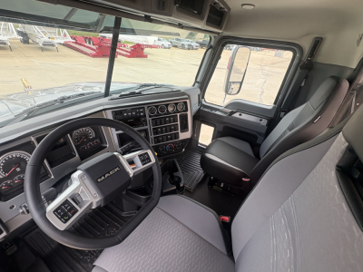 Interior of 2027 Mack PI64T truck cab showing steering wheel, dashboard with multiple gauges, center console, and driver seat.