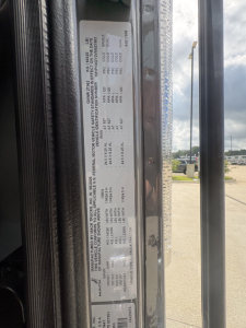 Label plate on Mack PI64T showing vehicle specifications and tire/wheel data with VIN1M1PN4GY2VM021953 and stock info.