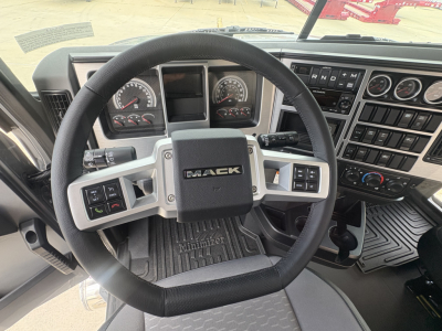 Steering wheel and dashboard of a 2027 Mack PI64T truck cab showing Mack emblem, instrument cluster, and control panels.