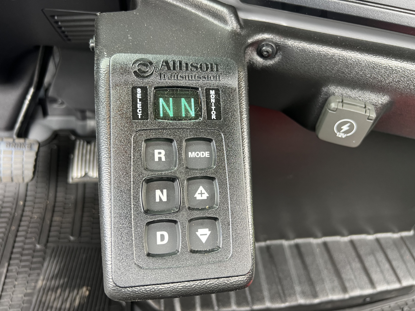 Alison Technologies electronic gear selector panel showing NN in indicator, R, N, D mode buttons, and charging port nearby inside Mack MD7 cab.