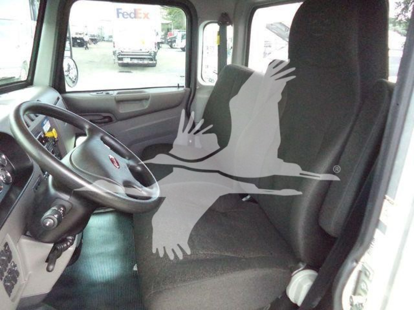 Truck cab interior of a 2022 Peterbilt 337 rollback showing steering wheel, driver seat, and dashboard with a watermark overlay.