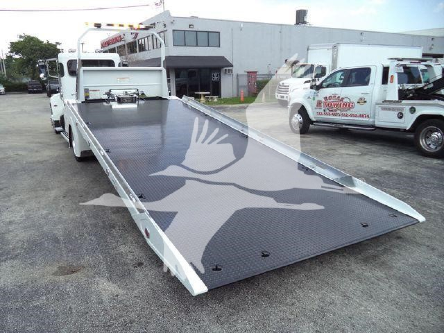 Peterbilt 337 rollback truck with hydraulic flatbed extended for loading.