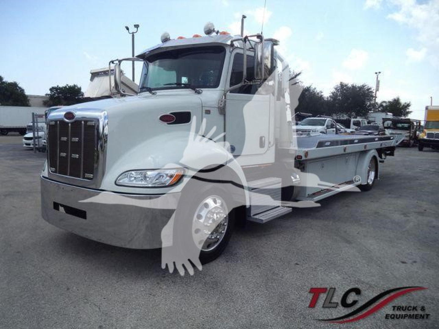 Peterbilt 337 rollback truck in white with long flatbed and chrome grille, side steps visible.
