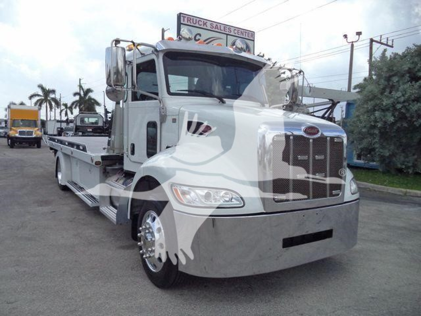Peterbilt 337 rollback truck in silver exterior, front view with chrome grille and hood, JT61994FM visible, logo on grille.