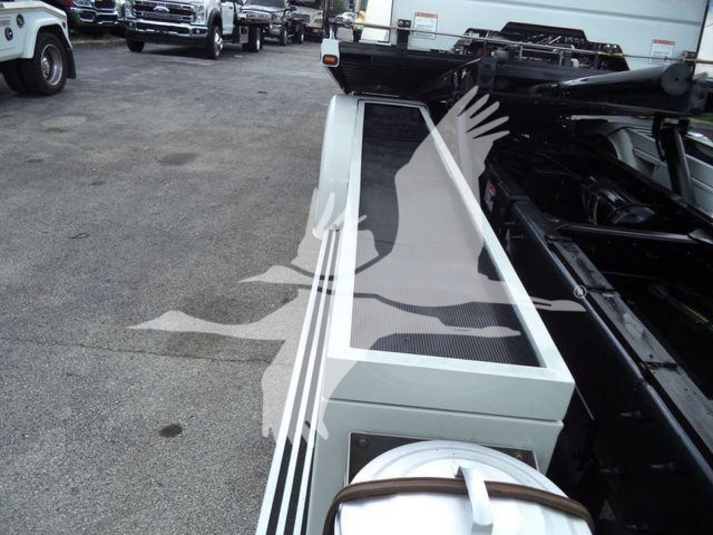 Peterbilt 337 rollback truck chassis with a metal toolbox and coiled hose reel; surrounding vehicles in a dealership lot.