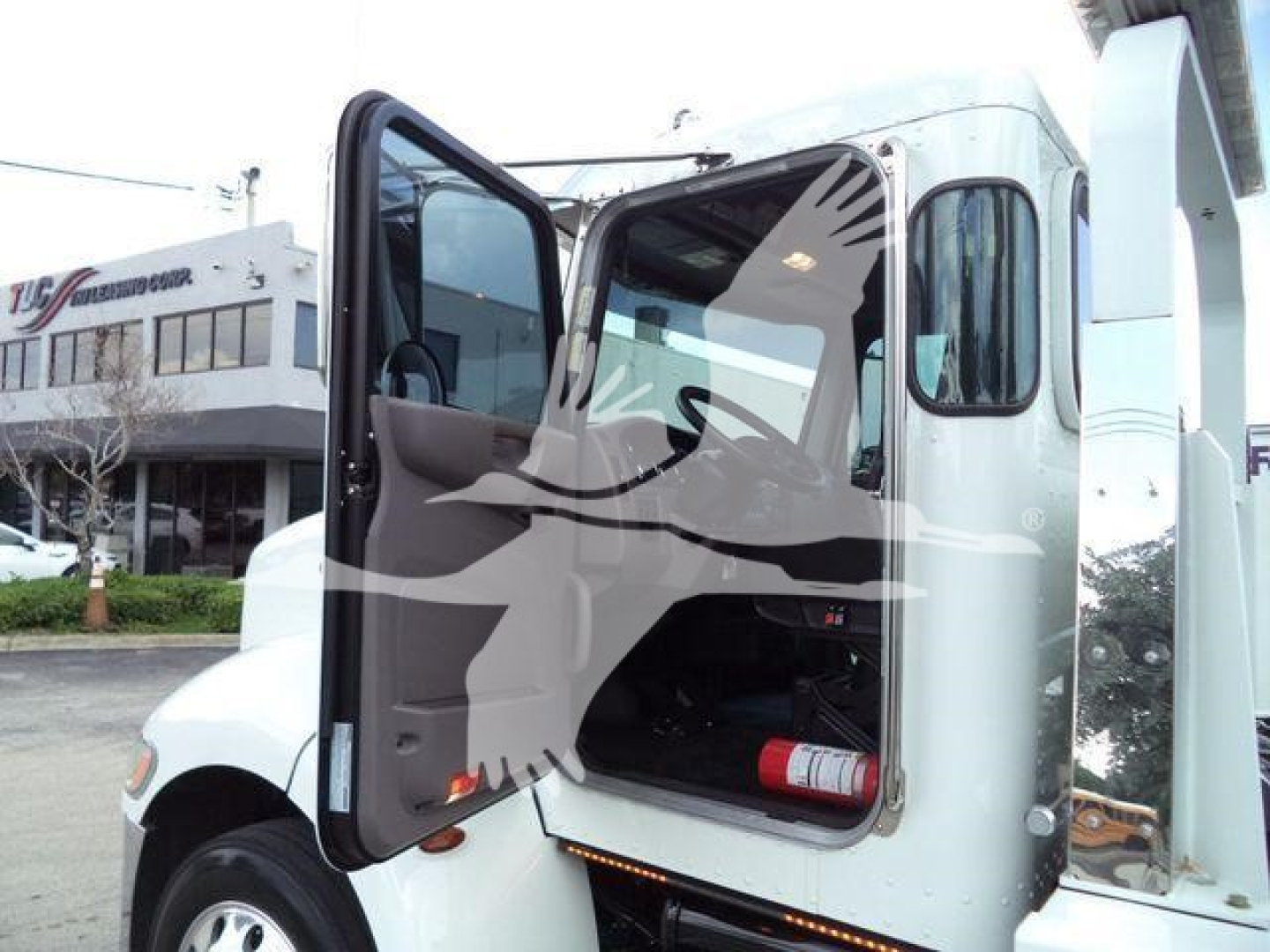 Truck cab interior view with door open showing Peterbilt 337 rollback truck. Visible text includes none clearly, front wheel and side door, open cab doorway.