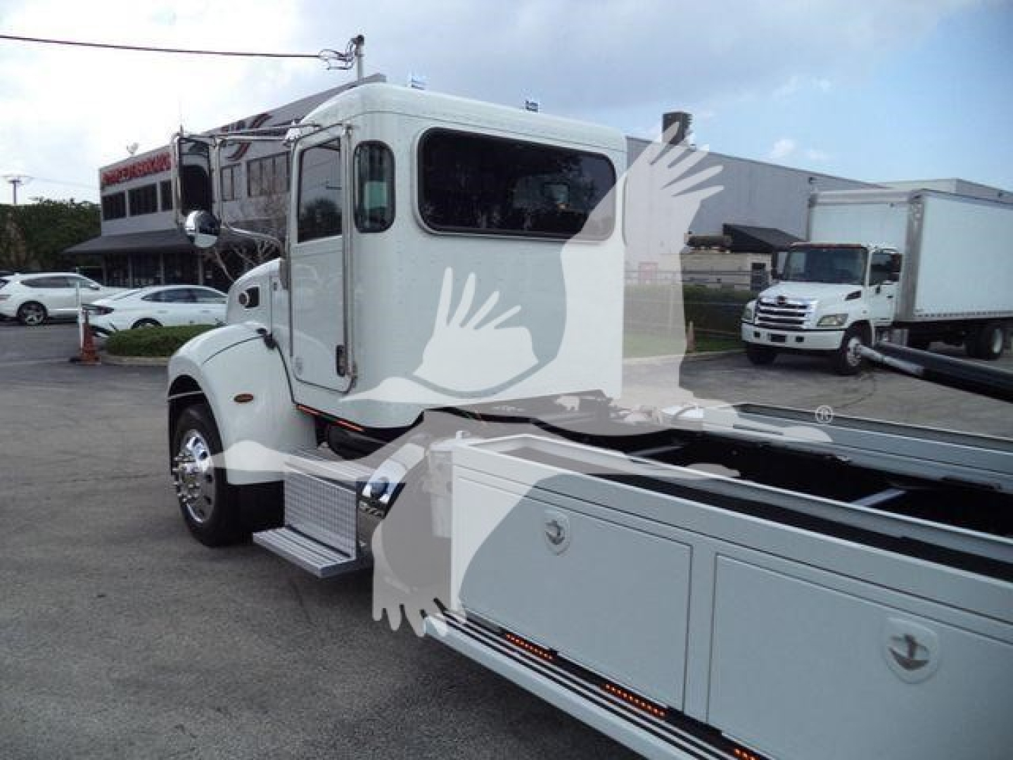 Trucker cab of a Peterbilt 337 rollback truck showing the front and side, white exterior with large windshield, chrome mirrors, and side steps.