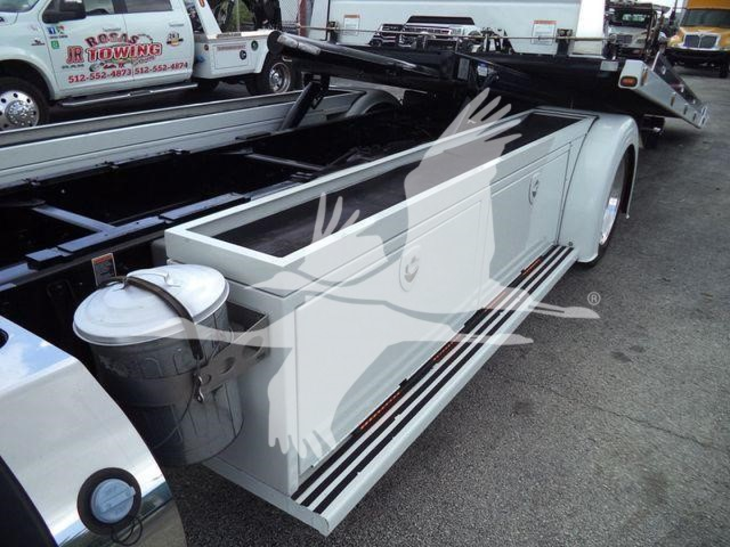 Peterbilt 337 rollback truck side view showing white utility compartments and dual fuel/maintenance tanks, with white body and chrome step rails.
