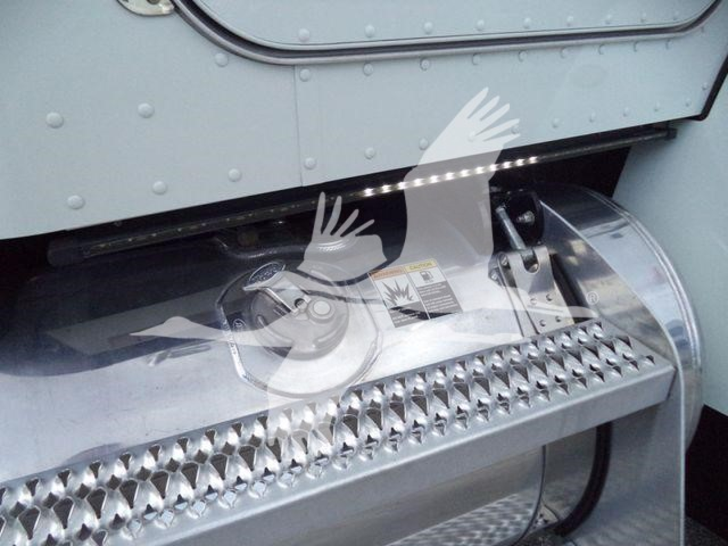 Truck rocker panel and chrome step with textured tread on Peterbilt 337 semi, blue gray body panel above, fuel/engine area visible.