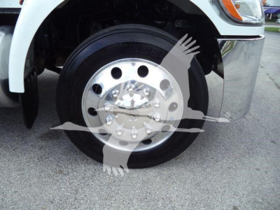 Front wheel and fender of a Peterbilt 337 rollback truck showing polished steel wheel with lug nuts and tire; no legible model text visible on the wheel.