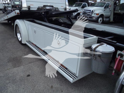 Peterbilt 337 rollback bed with sidestep panels and storage compartments, white exterior, rear view showing fuel or fluid canister on right side.