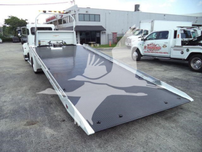 Peterbilt 337 rollback truck with hydraulic flatbed extended for loading.
