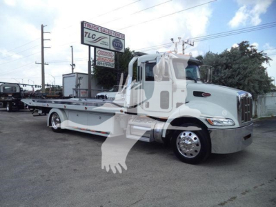 Peterbilt 337 rollback truck shown in side view with white cab and flatbed, dealership sign in background. Visible text on image includes TLC Truck Sales Center sign and other shop banners.