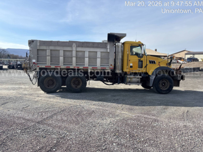 Dump truck side view showing cargo bed and cab with yellow front, Mack GU713 model likely. Visible text includes watermark and small VIN/stock details overlayed on image.