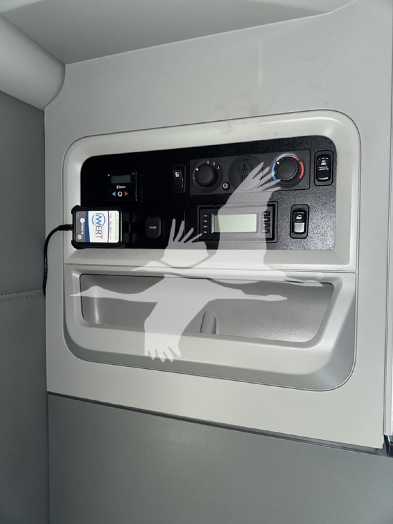 Dashboard panel in a Kenworth T680 sleeper cab showing controls, digital display, and small device plugged into a port.