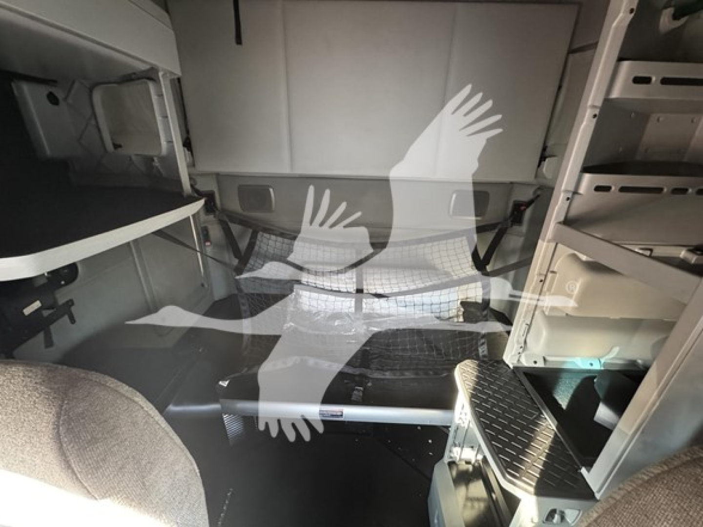 Kenworth T680 cab interior showing storage shelves and side panels in the sleeper area with metallic steps and a textured floor mat.
