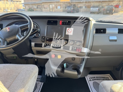 Kenworth T680 dash and steering wheel interior showing center console with controls and cup holders.