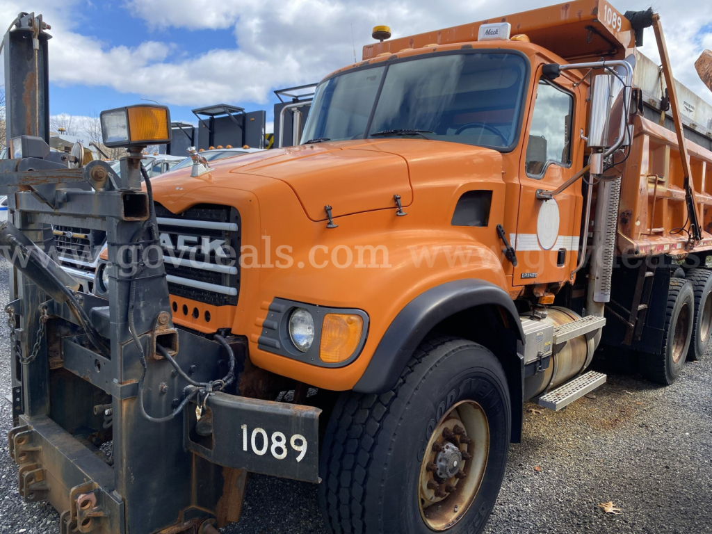 Mack CV713 Granite dump truck in orange with front bumper guard and side mirrors visible, showing number 1089 plate and heavy-duty hauling bed.