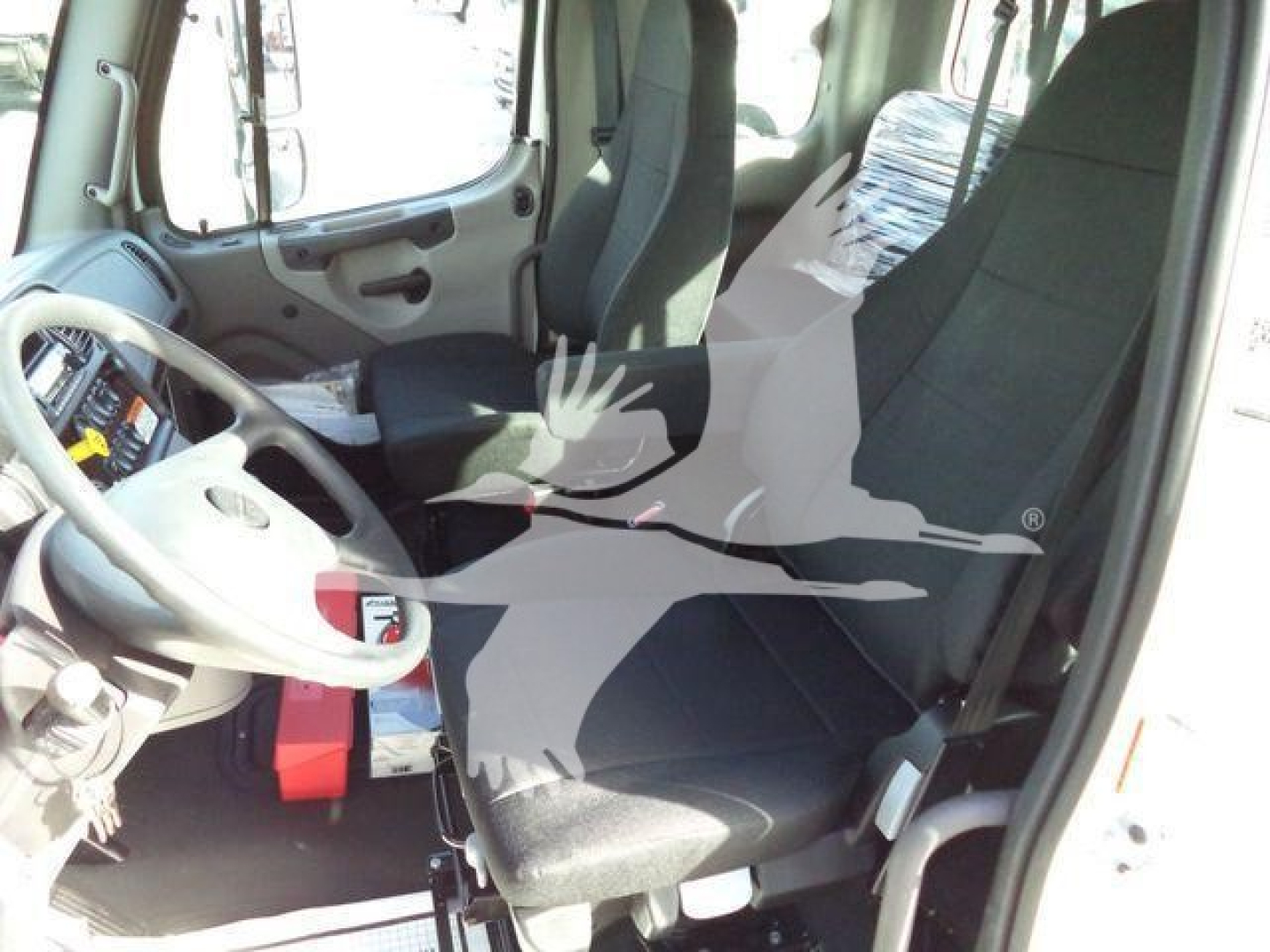 Freightliner M2 106 Plus truck cab interior showing steering wheel, driver seat, and dashboard with standard controls.