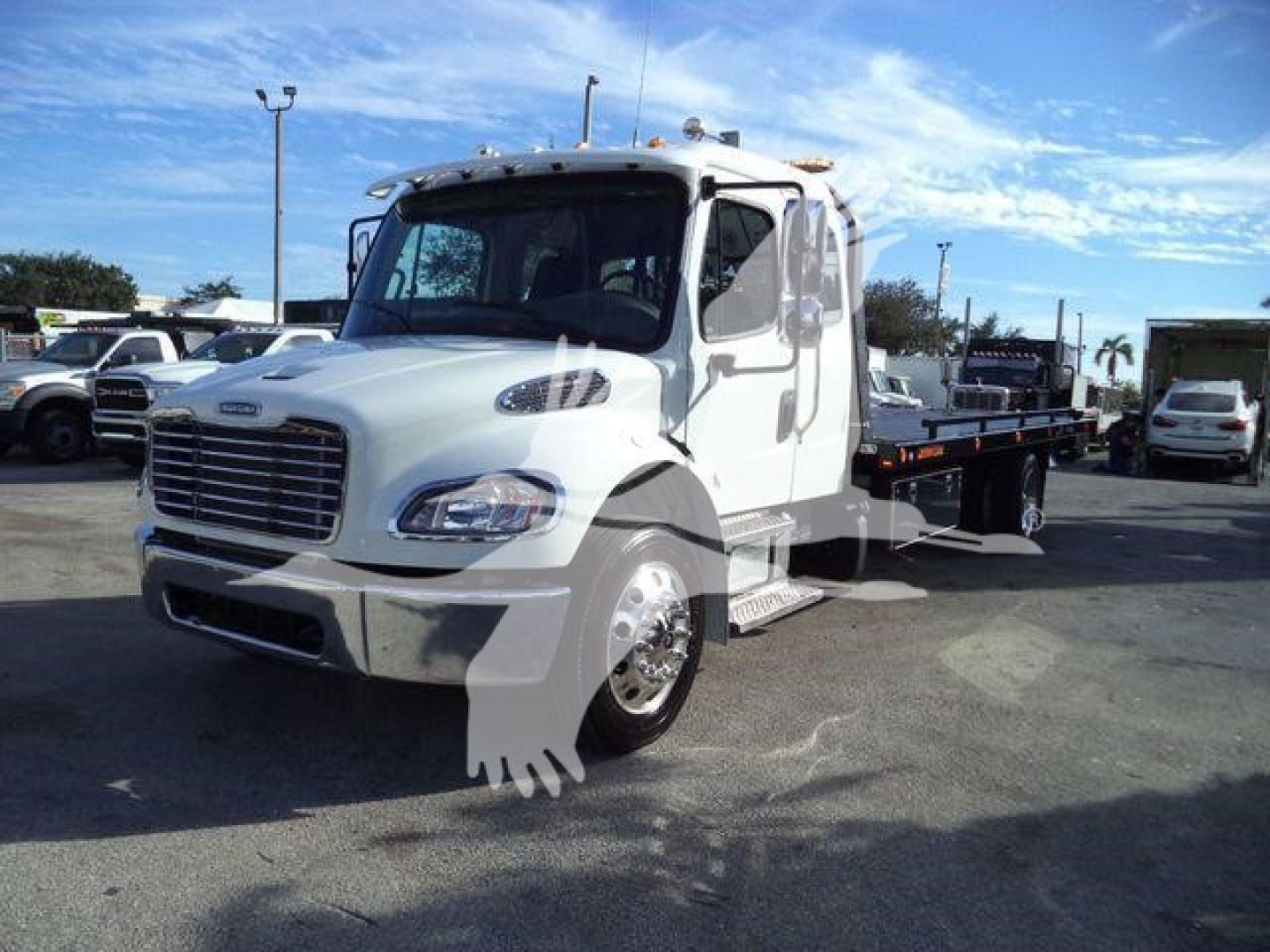 White Freightliner M2 106 Plus rollback truck with flatbed, front grille, cab, and mirrors visible; stock number JG8187 shown in listing context.