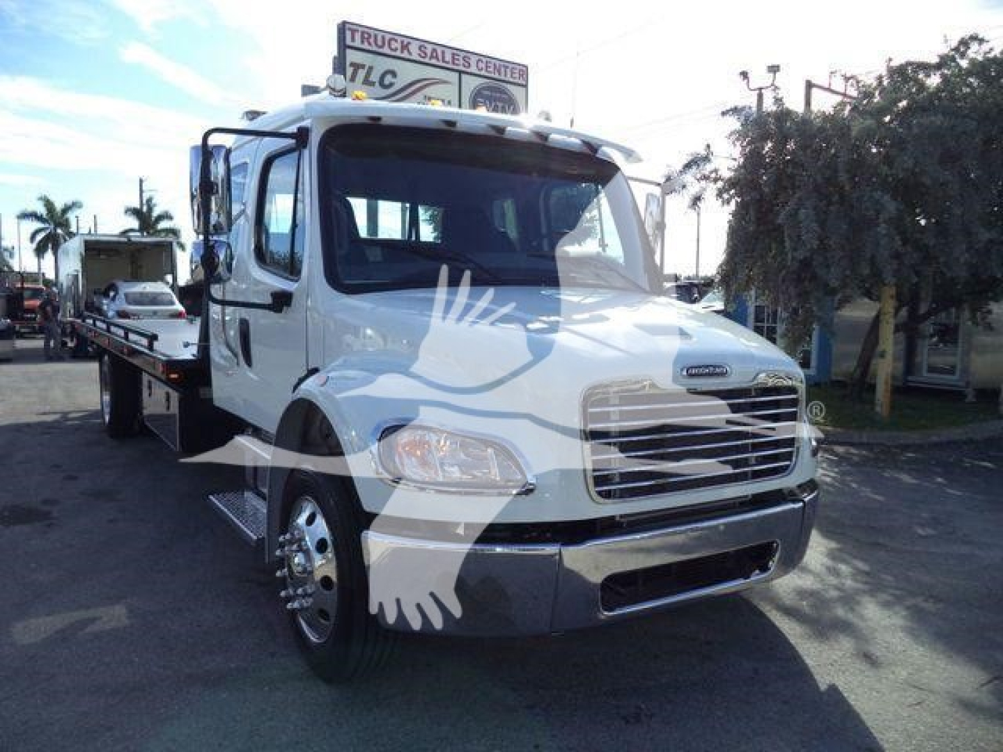 Freightliner M2 106 Plus rollback truck front-left view showing cab and flatbed in dealership lot, no visible text on labels.