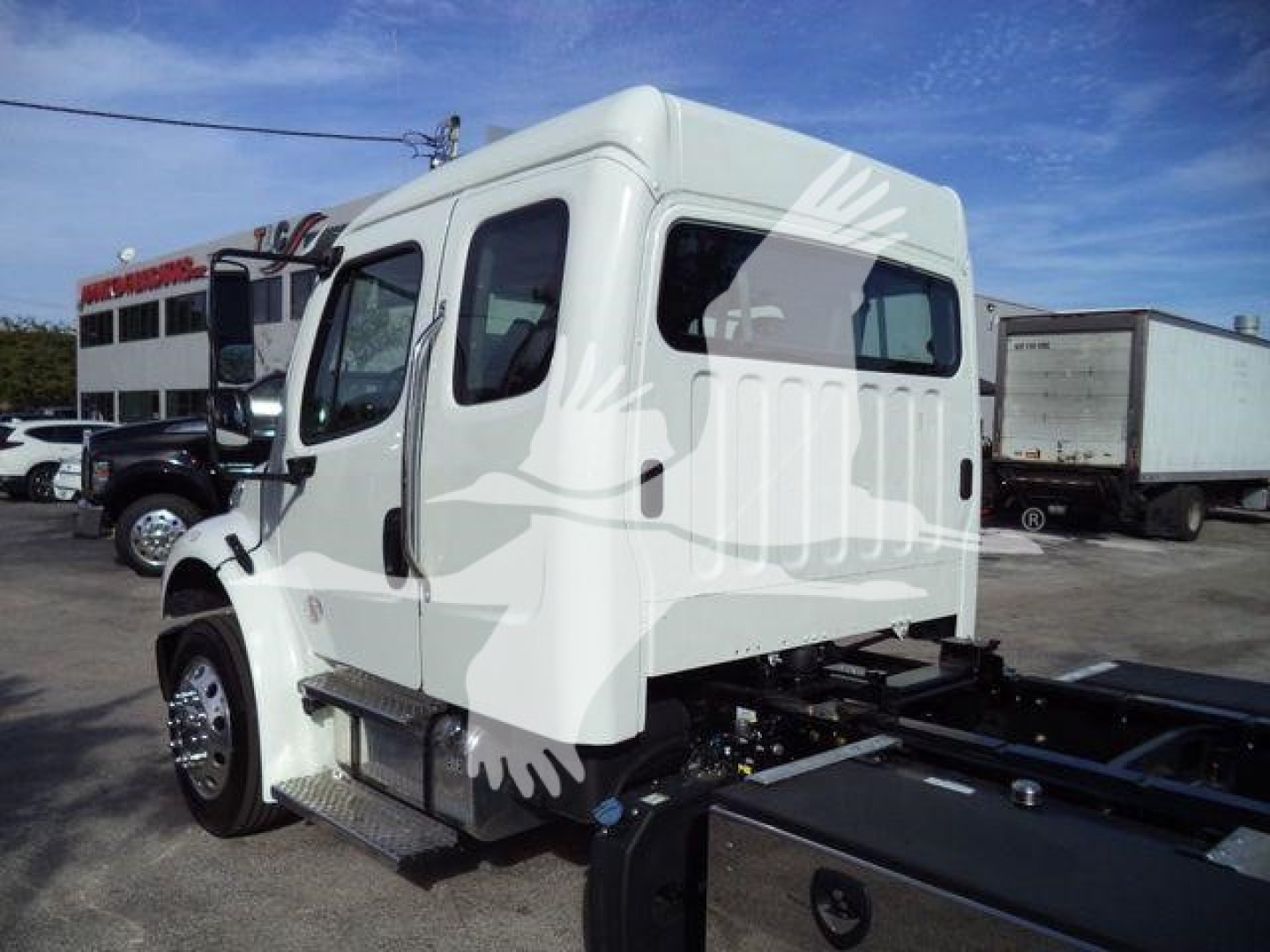 Truck cab side view showing Freightliner M2 106 Plus with white exterior and chrome wheels.