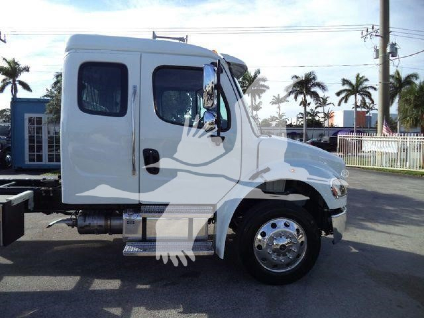 Truck side profile showing a white Freightliner M2 106 Plus cab with dual doors, chrome hubcaps, and fuel/air tanks under the cab