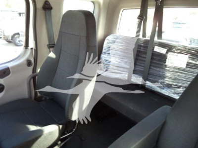 Cab interior of a Freightliner M2 106 Plus roll-back truck showing front seat and rear bench with protective wrapping over the rear window area.