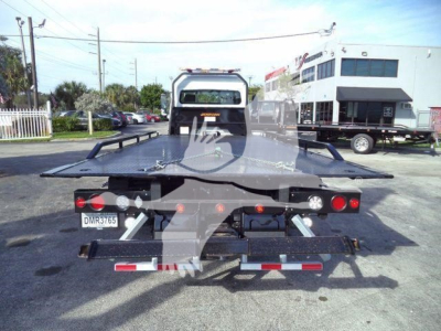 Flatbed tow truck bed of a Freightliner M2 106 Plus with rear lights and license plate visible.