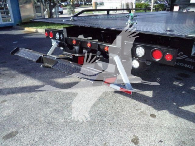 Rear view of a Freightliner M2 106 Plus rollback truck showing twin fold-down asphalt ramps and rear lighting, with platform and bumper details visible.