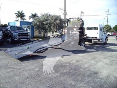  Freightliner M2 106 Plus rollback truck with flatbed in parking lot showing equipment and two trucks nearby.