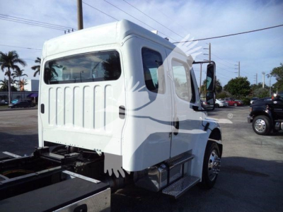 Truck cab in white, rear view showing side steps and underbody, Freightliner M2 106 Plus chassis, no visible text on panels.