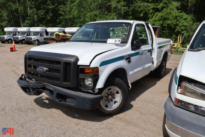Ford F-250 Super Duty pickup truck in a yard, white with blue/green stripe, front bumper damaged, right side cab door open, other vehicle nearby.