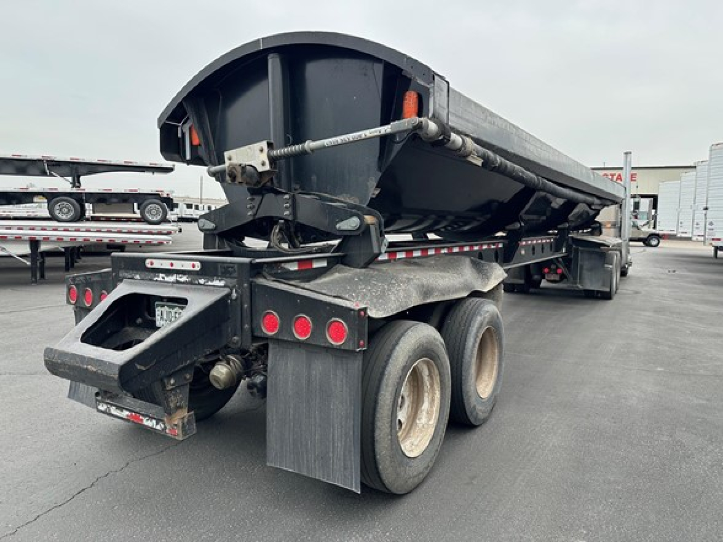 Trailer rear view of a 2013 Jet Air Ride Jet Side Dump, showing dump body, dual rear axles, mudflaps, tail lights, and hitch area with hydraulic components.