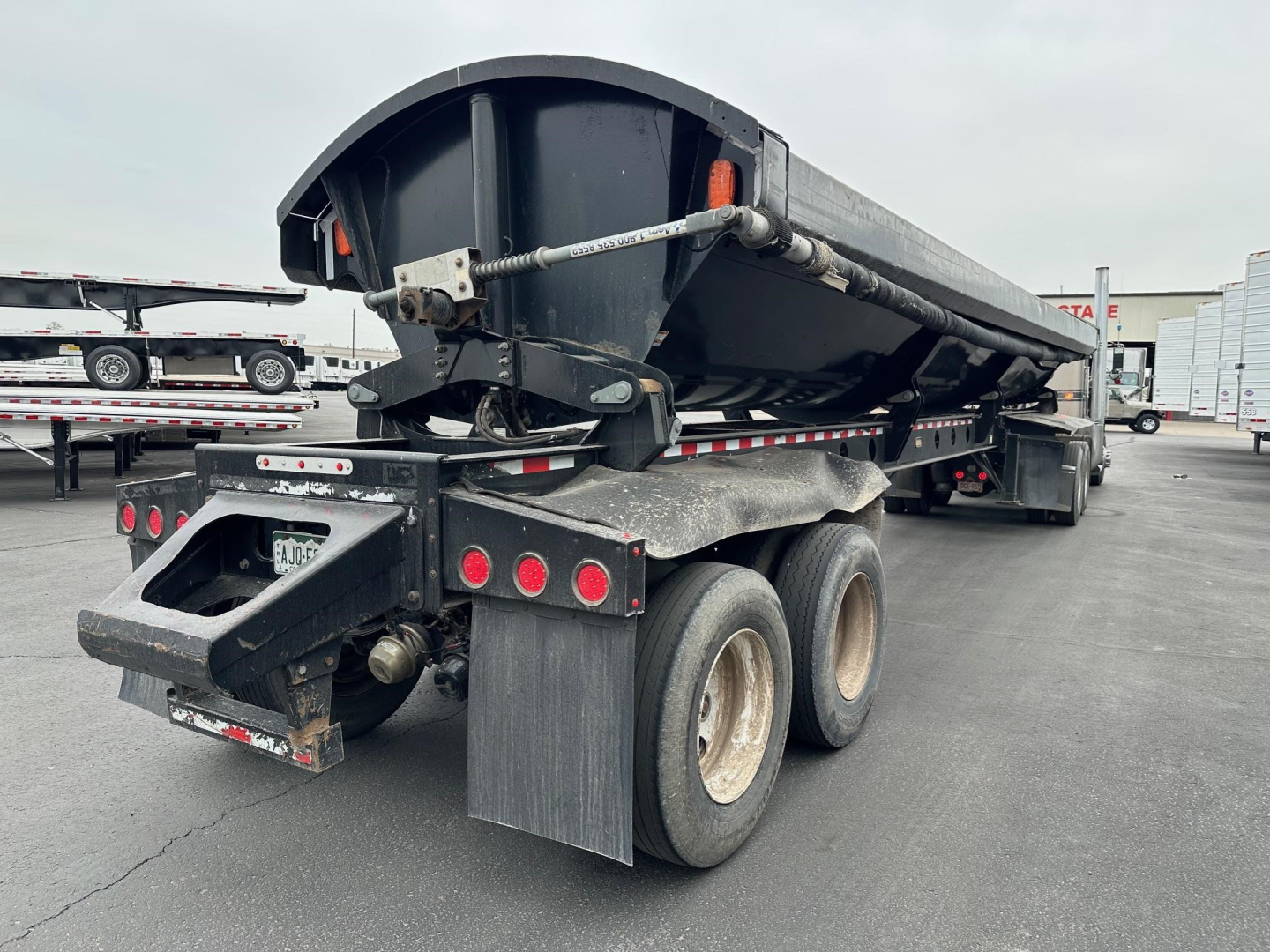 Trailer showing a side-dump dump trailer with dual rear axles and mud flaps.