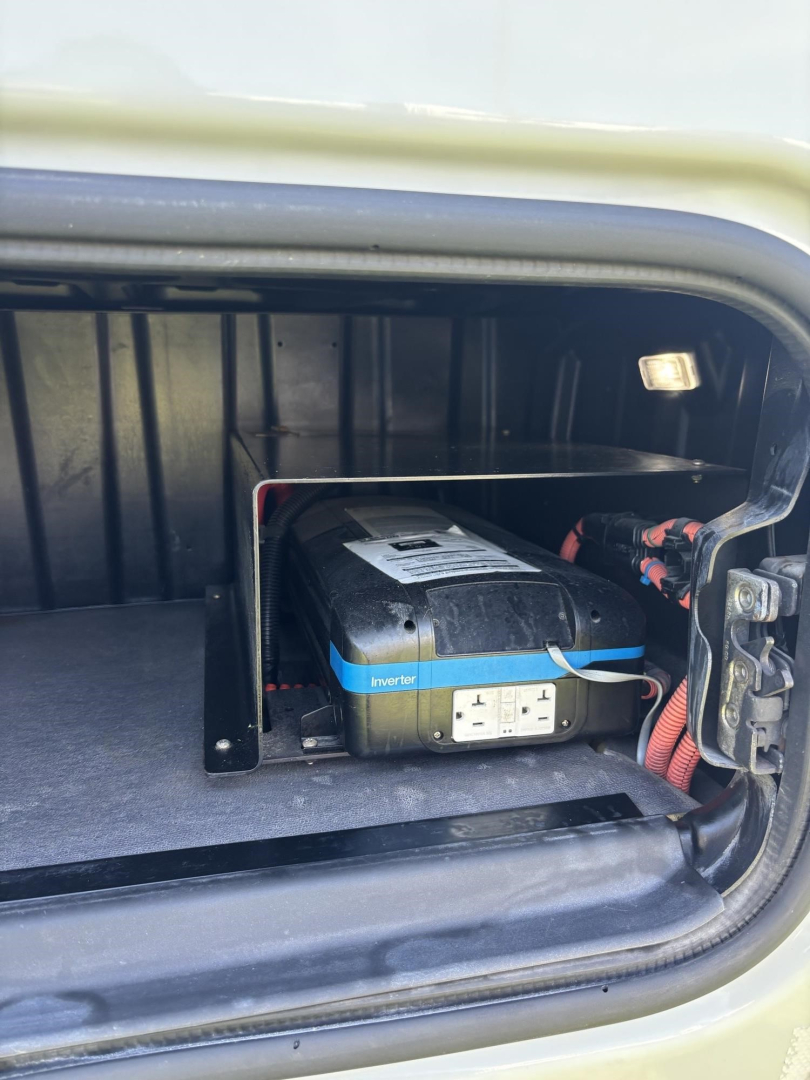 Freightliner Cascadia 126 engine bay area showing auxiliary inverter in storage compartment.