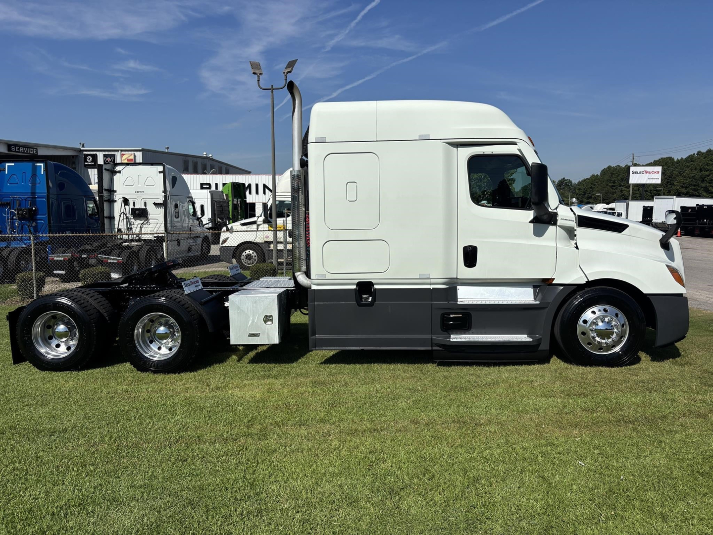Truck side view of a 2021 Freightliner Cascadia 126 semi-truck cab with white exterior and black lower paneling, 6x4 axle configuration visible in trailer area.