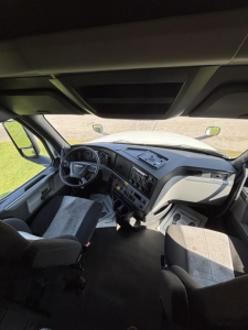 Interior cabin view of a Freightliner Cascadia truck driver area with steering wheel, dashboard controls, and seats visible.