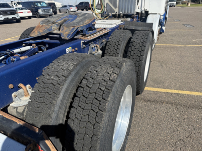 Kenworth T880 chassis showing dual rear axles and tires, blue frame, fuel/air lines and fifth wheel assembly visible.