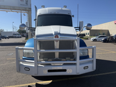 Kenworth T880 conventional sleeper front view with chrome grille guard, blue fenders, large bumper, and dual round mirrors.