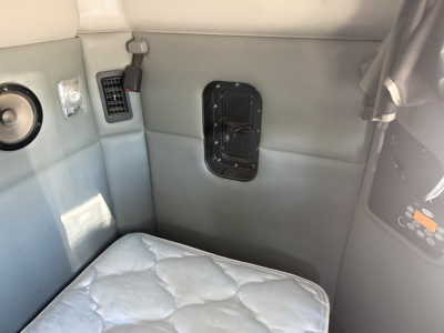 Kenworth T880 interior detail showing sleeper cab with window vent, control panel, and light gray upholstery. 2016 model spec text not visible.