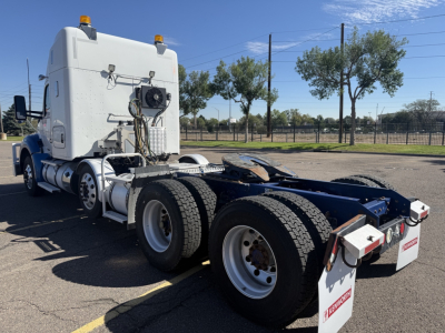 Kenworth T880 tractor rear with dual rear axles and fifth wheel, white sleeper cab, orange beacon lights, dual fuel tanks, and chrome exhaust stacks.