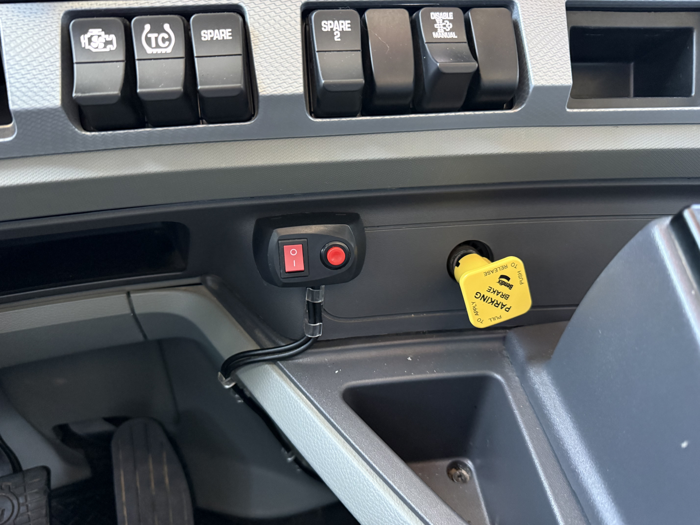 Kenworth T880 dash area showing ignition and yellow towing/engine shutoff tag, with assorted switch controls visible.