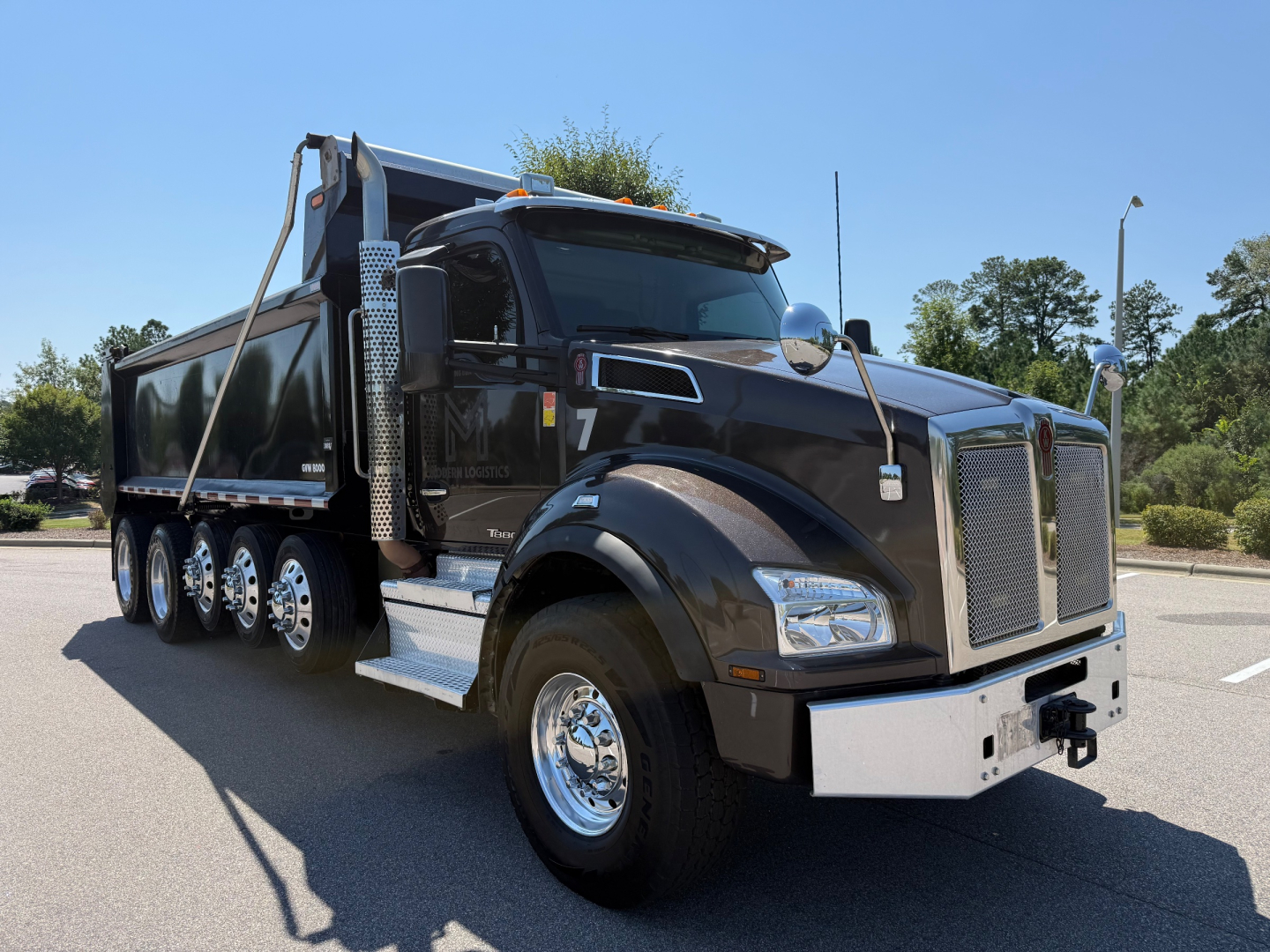 Kenworth T880 dump truck in service showing chrome front bumper and large grille, dump bed, and multiple rear axles.
